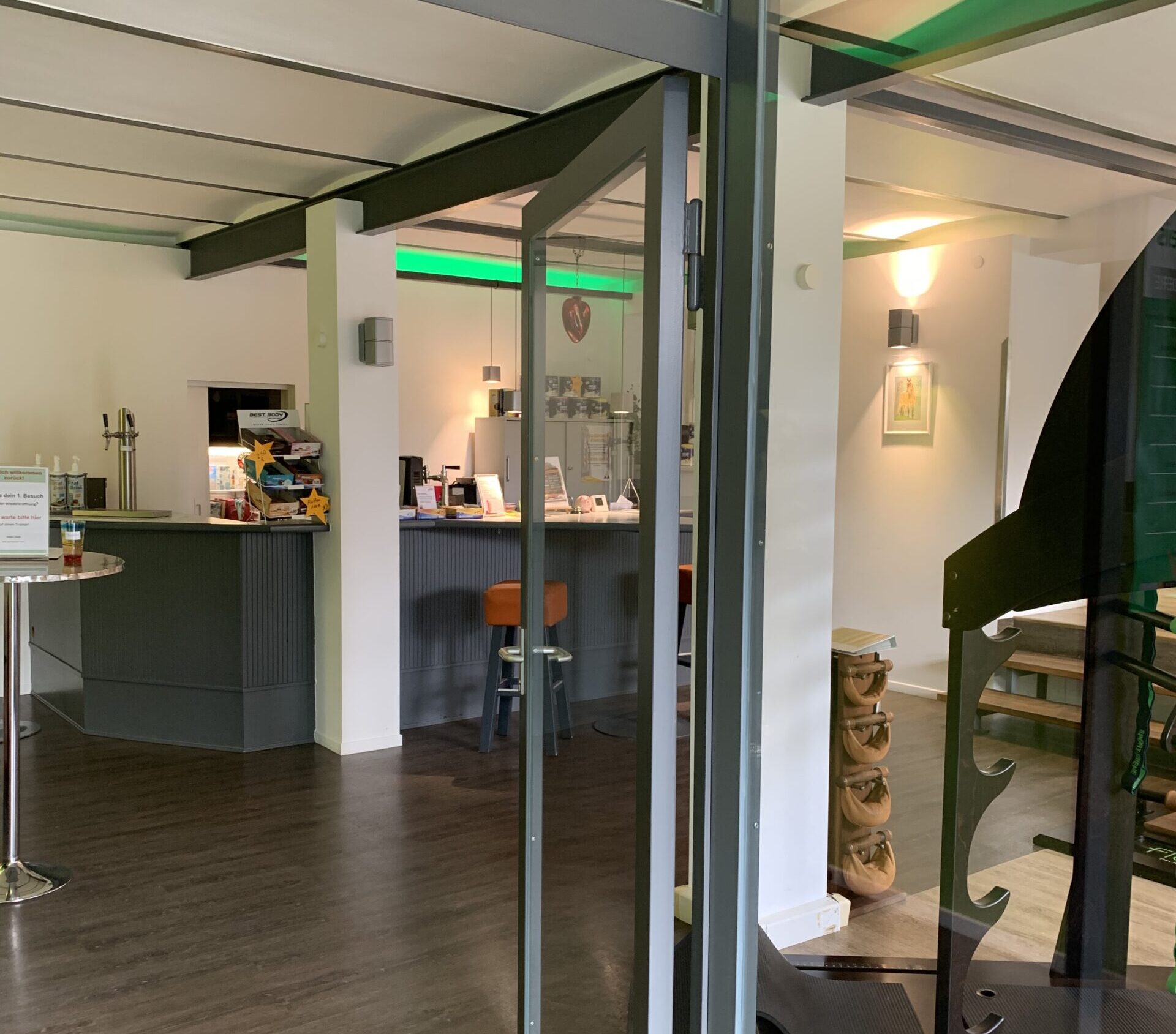 Eingangsbereich des agil Training & Therapies in Ahnsen. Zu sege ist der Service-Thresen, an dem Kaffee und Proteinshakes ausgeschenkt werden. Neben dem Theresen befindet sich ein Sit-in Bereich und rechts im Bild ist das Flexx Beweglichkeitstraining zu sehen